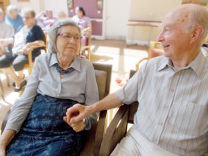 La Fontana Care home Martock resident and loved one holding hands during musical entertainment
