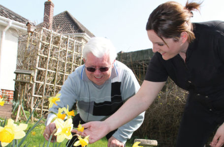 Notaro Care Assistant with service user looking at the daffodils in the garden