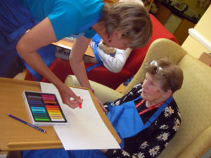 Susannah working with a resident on her butterfly pastel art