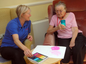 Pauline, activities coordinator helping resident with her butterfly artwork