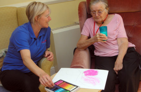 Pauline, activities coordinator helping resident with her butterfly artwork