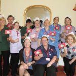 Staff team at Clarence Park, wearing nurse hats and waving flags for Nurses Day