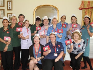 Staff team at Clarence Park, wearing nurse hats and waving flags for Nurses Day