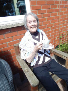 Resident sat in the garden with a cup of tea