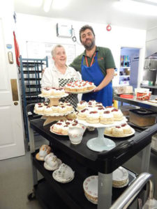 Chef, Janet with kitchen assistant next to a trolley full of Janet's homemade scones and cupcakes