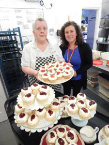 Janet holding a tray of her homemade cupcakes, with Cedar Lodge staff member