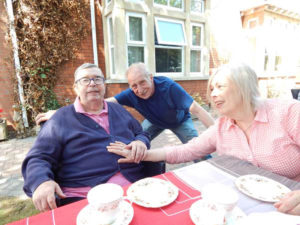 residents and relatives in the garden enjoying tea and scones