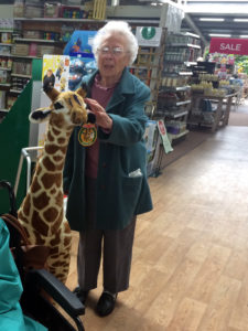 Resident petting a tall giraffe toy at the garden centre