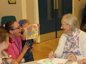 One of the children showing her painting to resident, Georgie