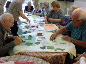 Mary with residents and staff, making leaf prints on paper