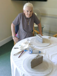 Resident with her finished slice of cake made from clay