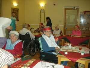 Residents at the table wearing Christmas hats