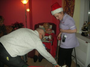 Resident in her room with loved ones, receiving Christmas present