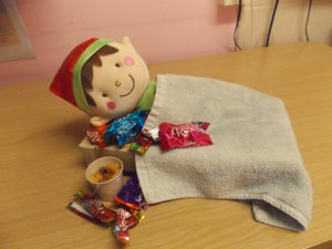 Elf in bed feeling sick after eating too many chocolates