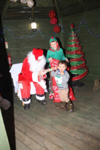 Father Christmas and his Elf giving out presents the children at the Limes Christmas Party