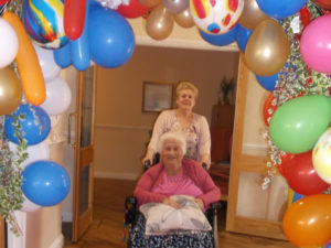 Teresa, Home Manager with Resident walking through the balloon arch on the red carpet