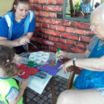 Resident and children painting butterfly pictures