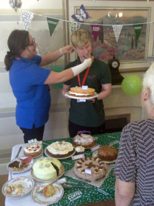 Immacolata house Care home domestic assistant, Ben receiving his award for best cake at their macmillan coffee morning